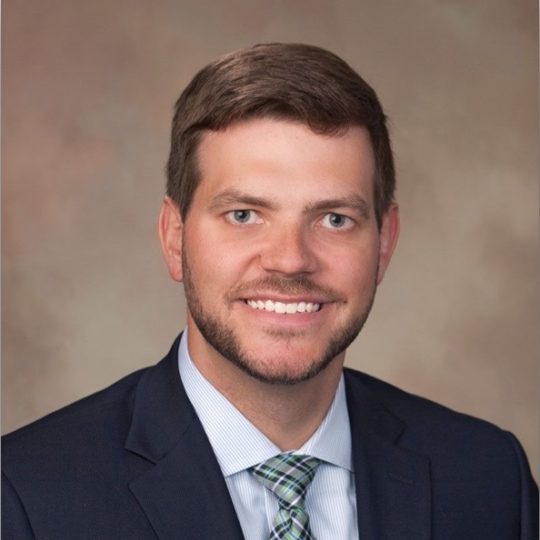 a man wearing a suit and tie smiling at the camera