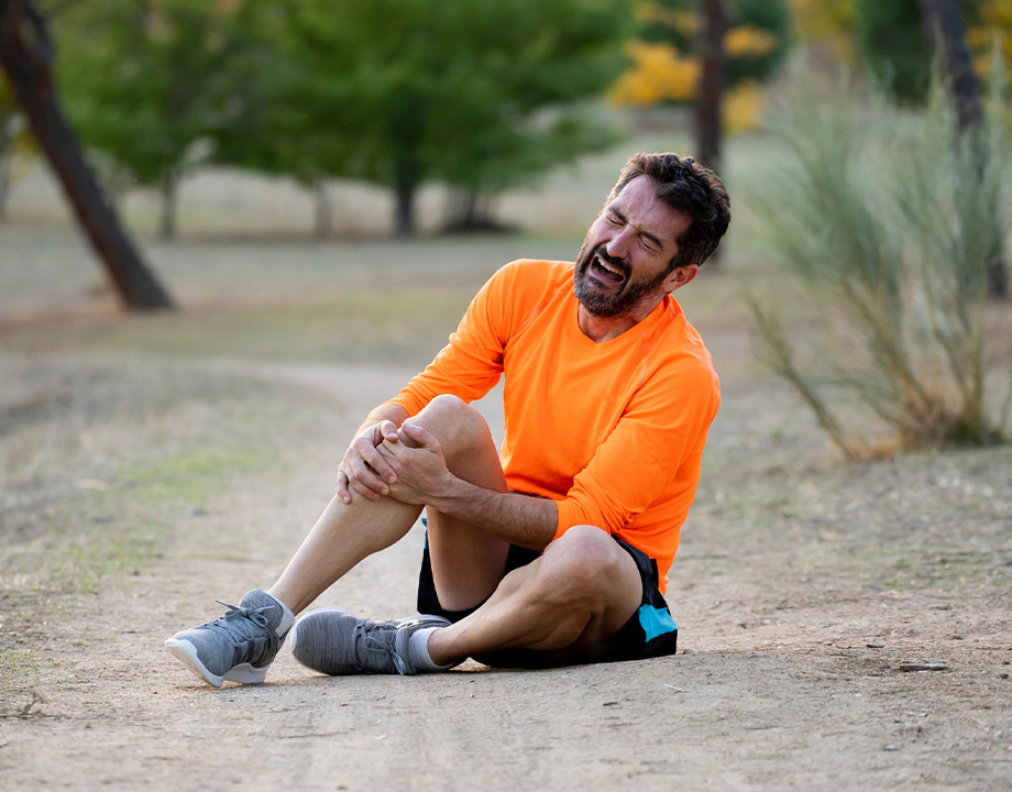 a man after running sitting on the ground with strong knee pain