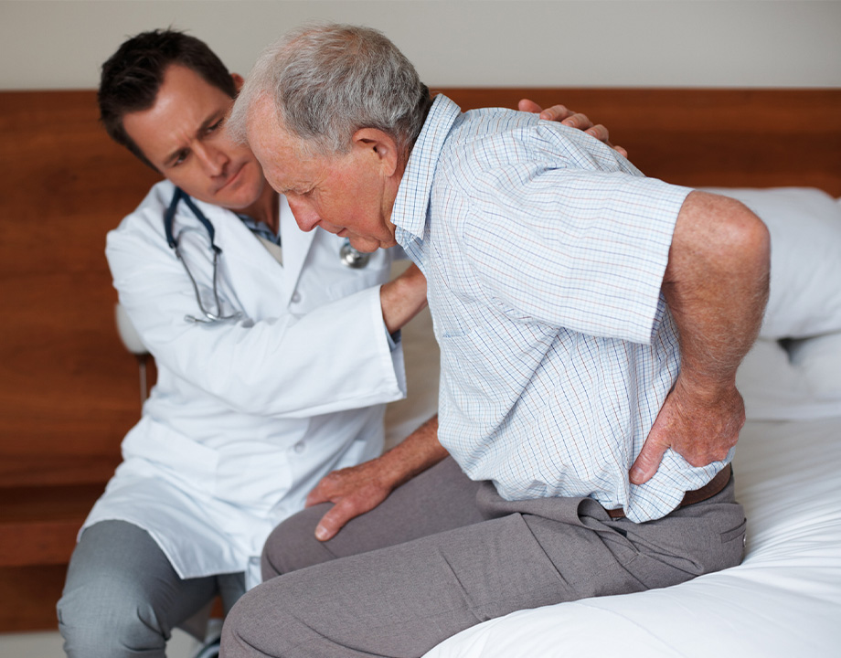 a man sitting on a bed with back pain and doctor checking on him