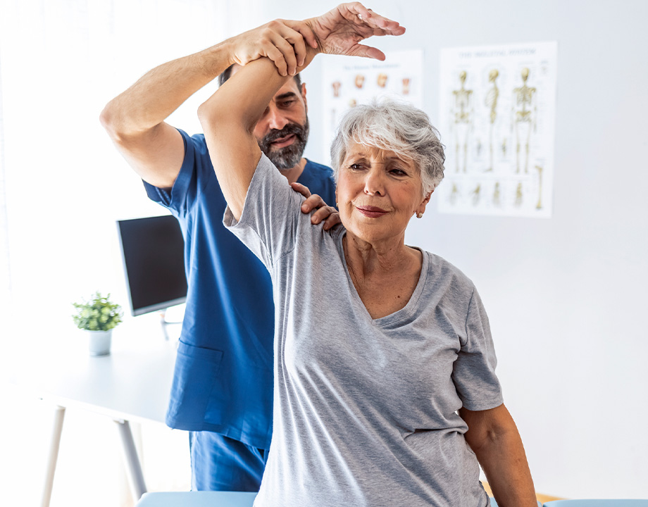Doctor helping woman with shoulder pain