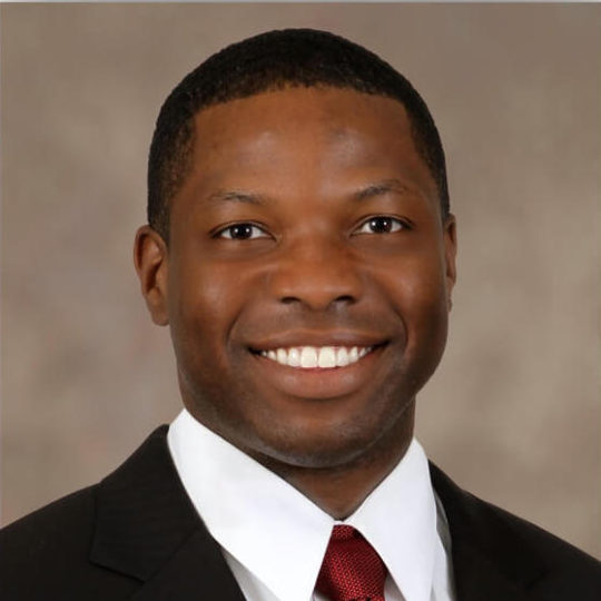 a man wearing a suit and tie smiling at the camera