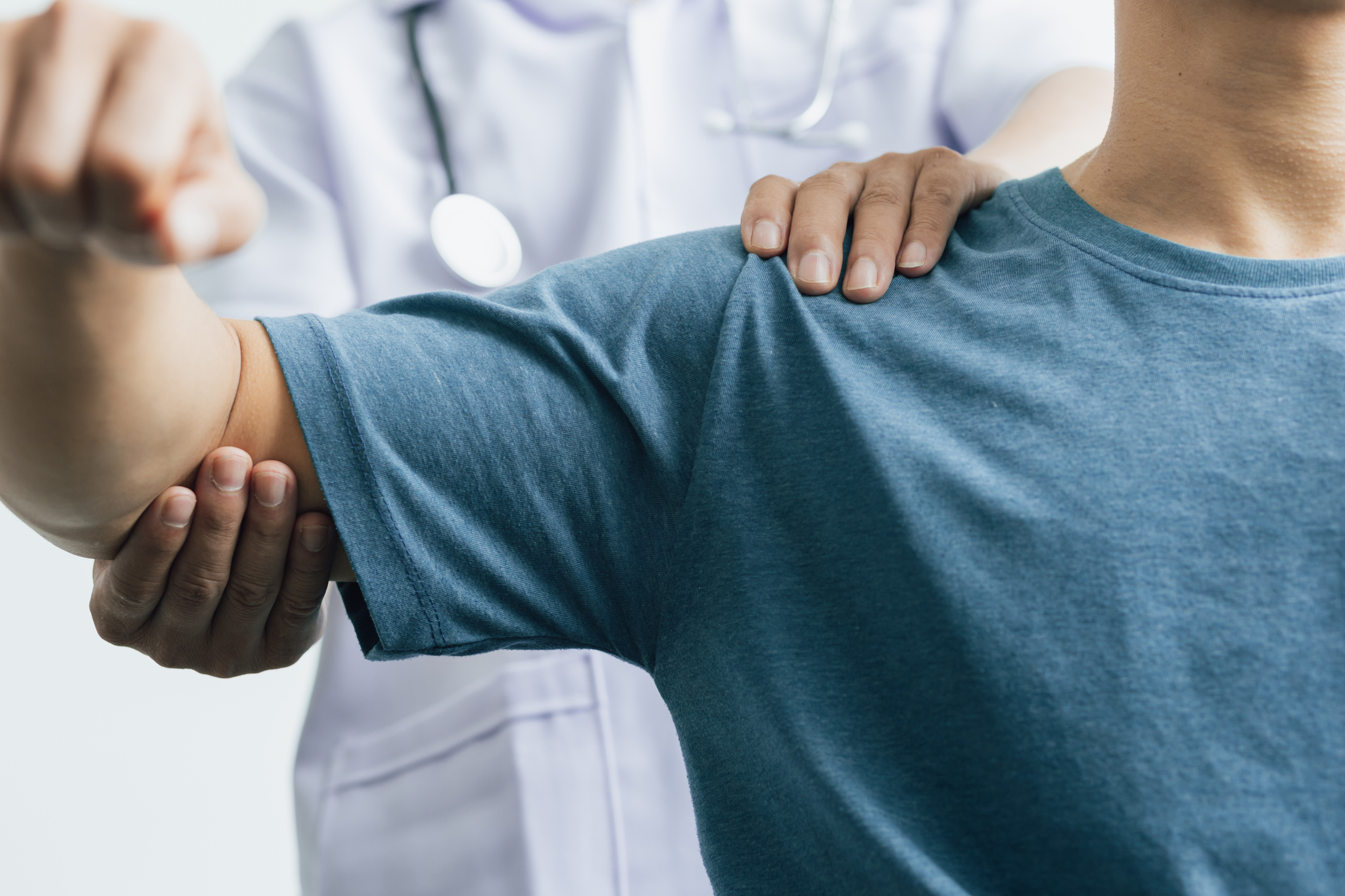 A doctor is aiding a man in shoulder rehab, offering support and advice for his arm's recovery process.