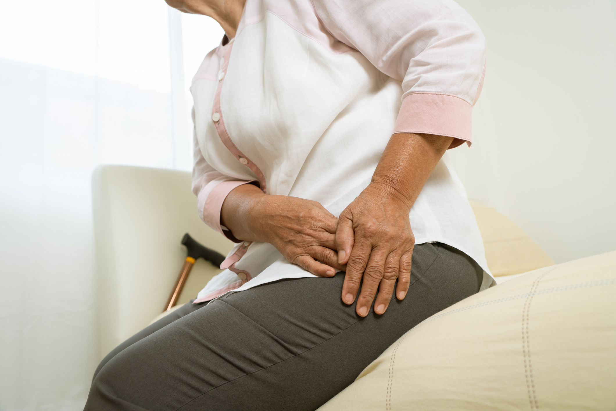 A person holding their hip in pain while sitting, illustrating hip pain that worsens at night as an orthopedic warning sign.